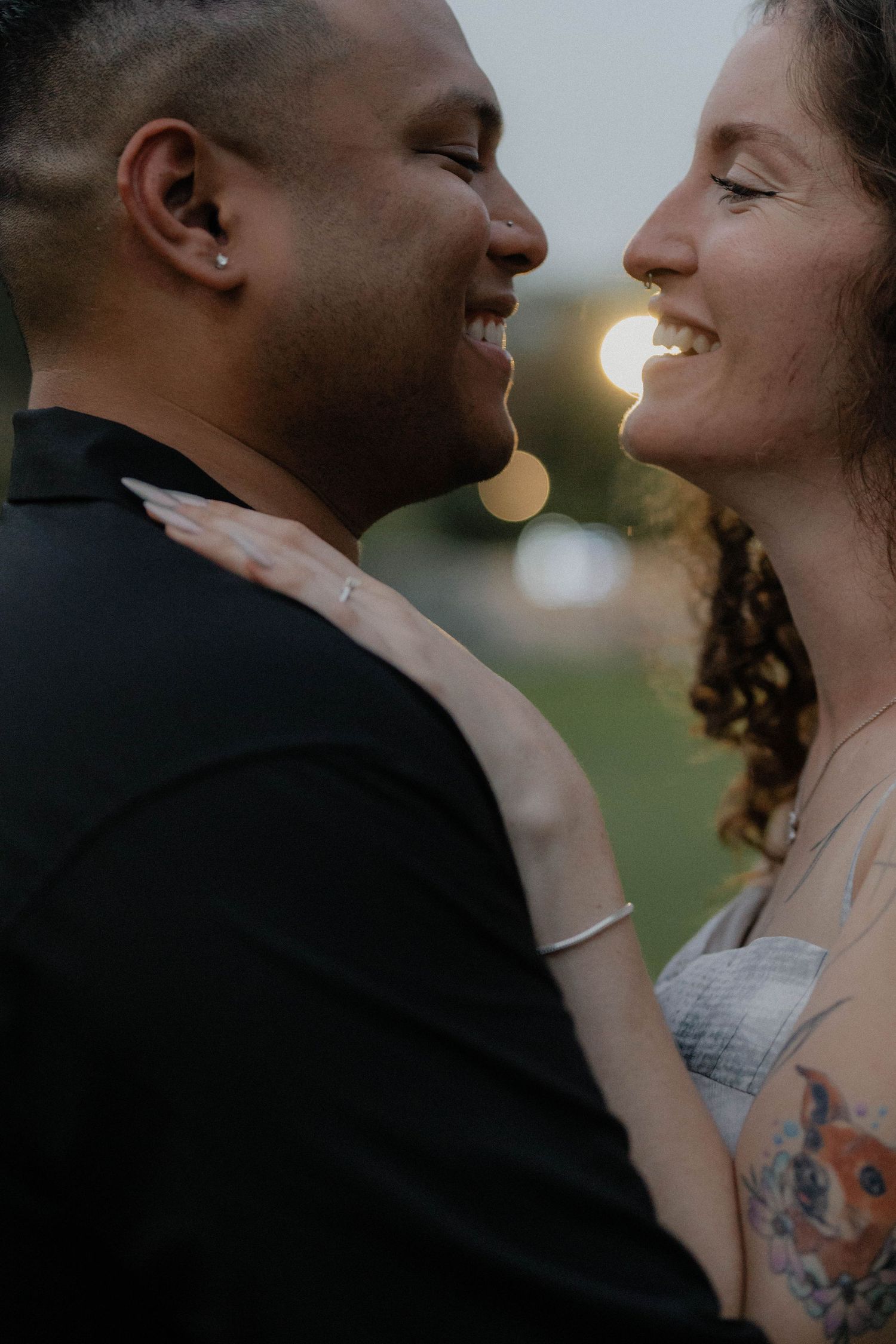 Romantic couple sharing an intimate moment at sunset with soft golden lighting.