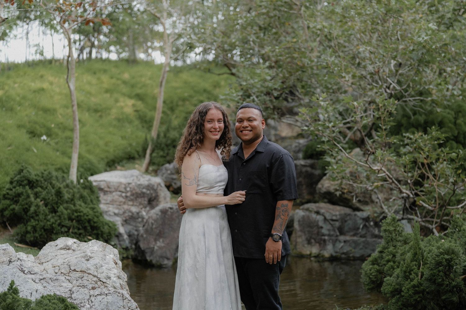 A couple sharing intimate moments during their wedding photoshoot in a garden setting.