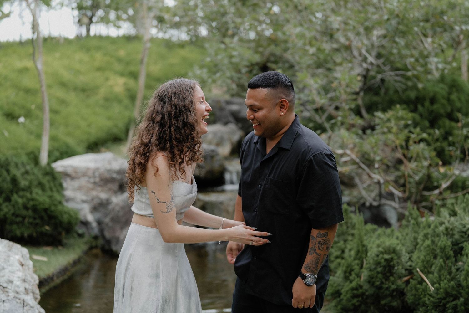 Couple shares emotional moment near a garden waterfall feature.
