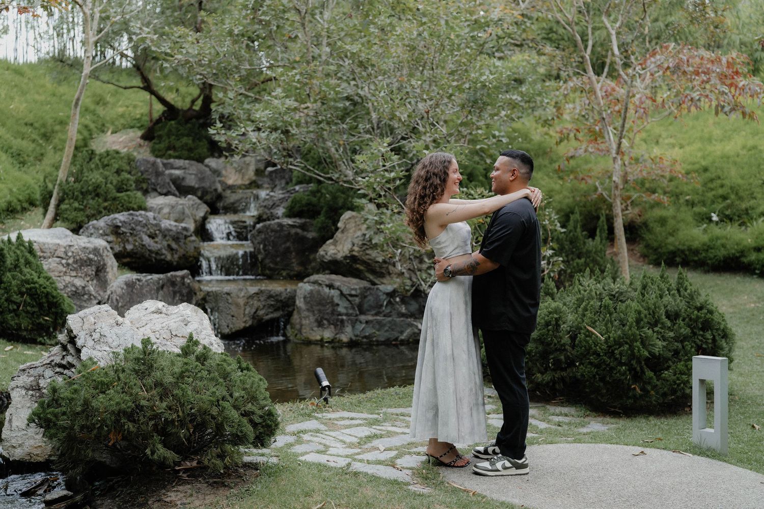 A romantic moment captured by a garden waterfall.