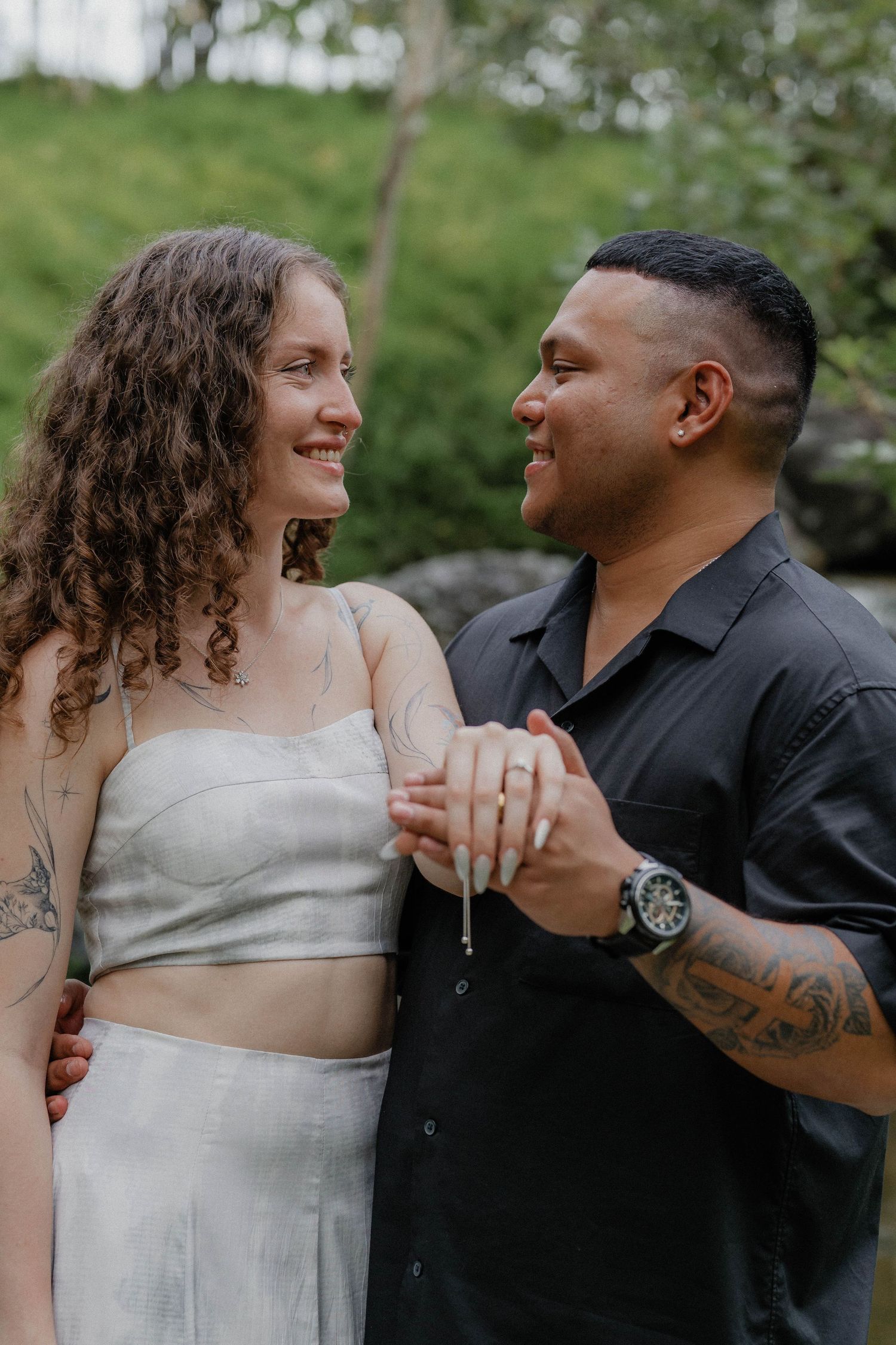 A couple shares a romantic moment outdoors, dancing together against a green garden backdrop.