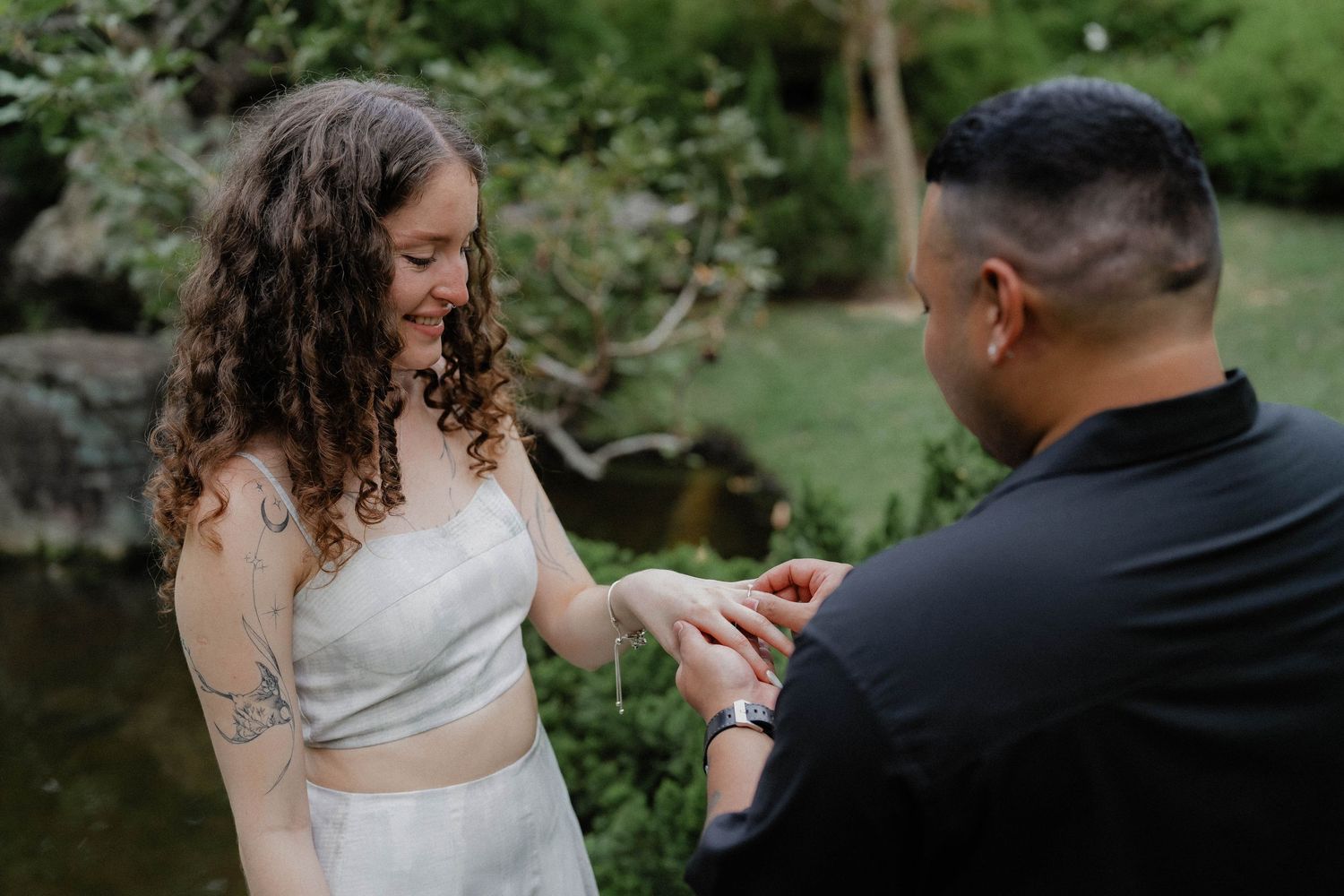 Joyful outdoor proposal scene with engagement box in a natural garden setting.