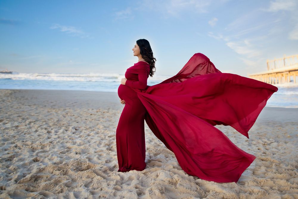 pregnant lady wearing a flowing marron dress on the beach