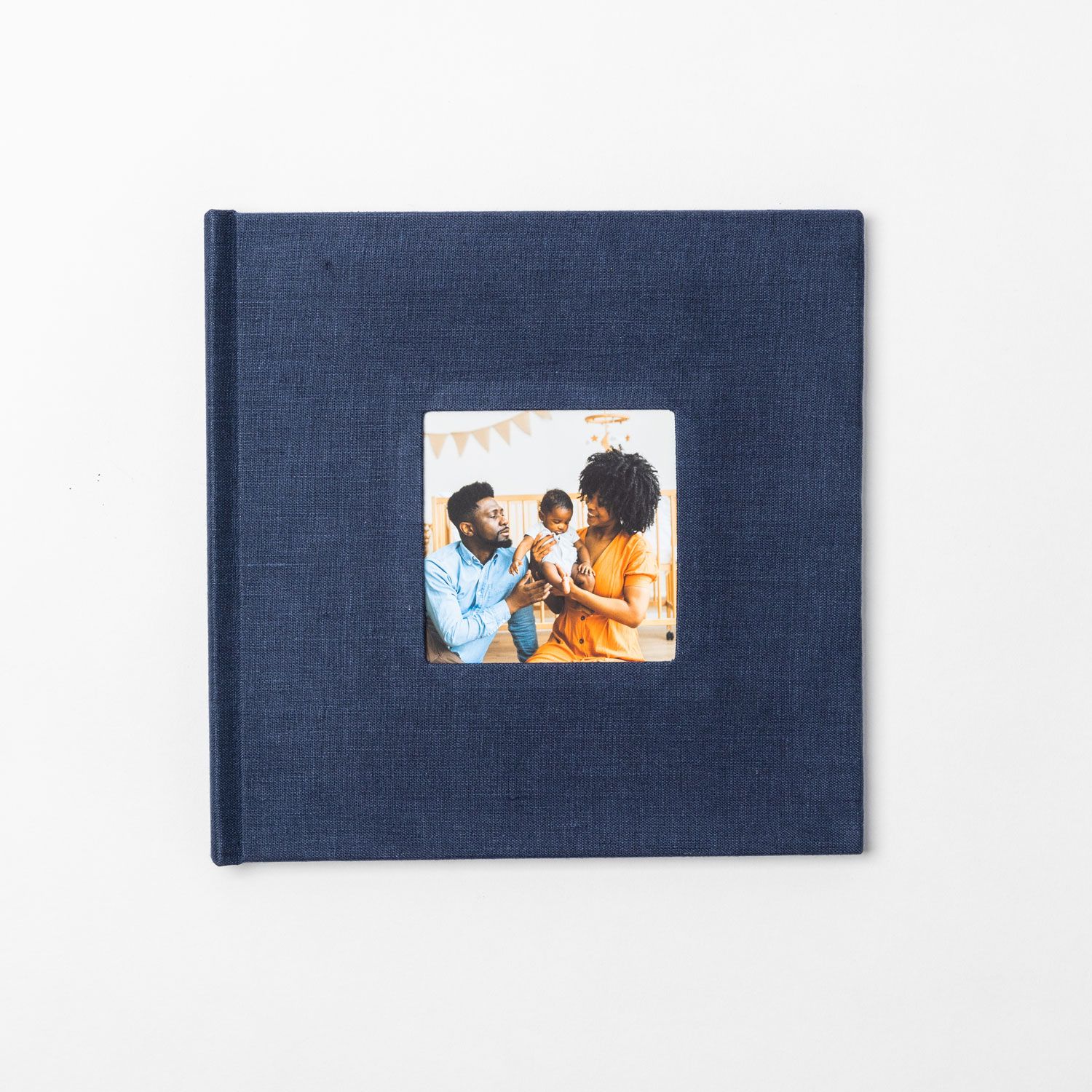 Navy blue photo album lies flat on white surface with small decorative photo insert on cover.