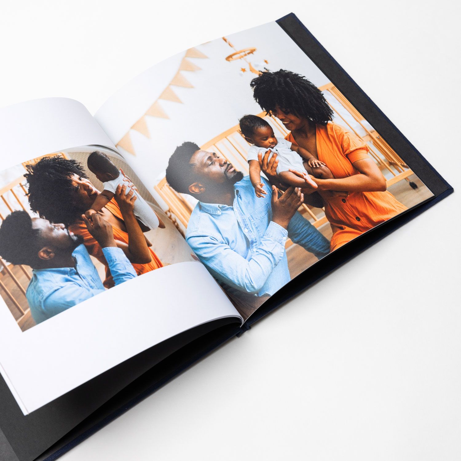 Open photo album showing two similar heartwarming family moments side by side on white pages against a white background.