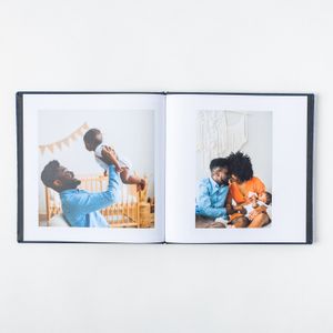 Open photo album showing joyful family moments with baby on two side-by-side pages.