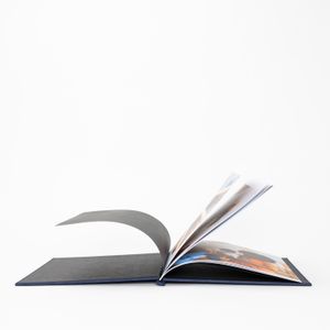 An open photo book with turned pages against white background showing minimalist artistic composition.