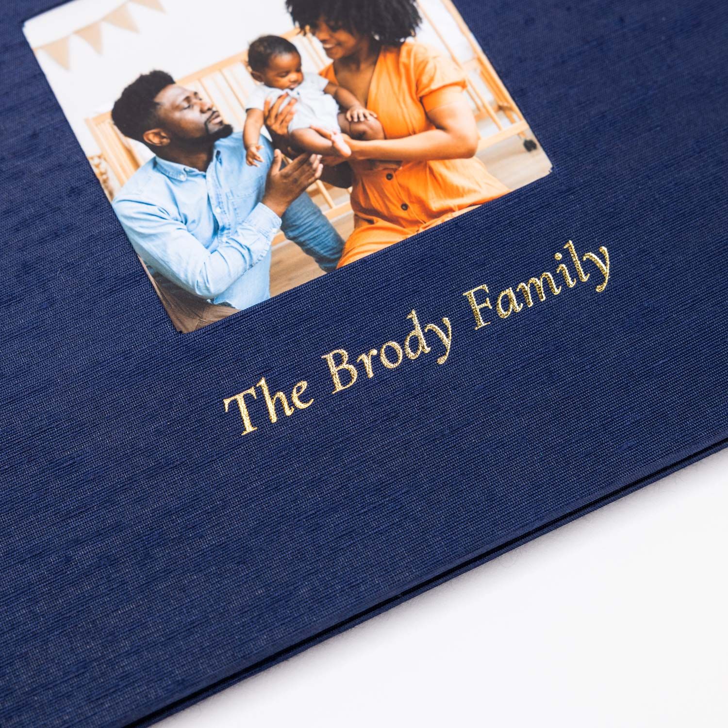 Navy blue photo album cover showing a family portrait photo and "The Brody Family" text in gold lettering.