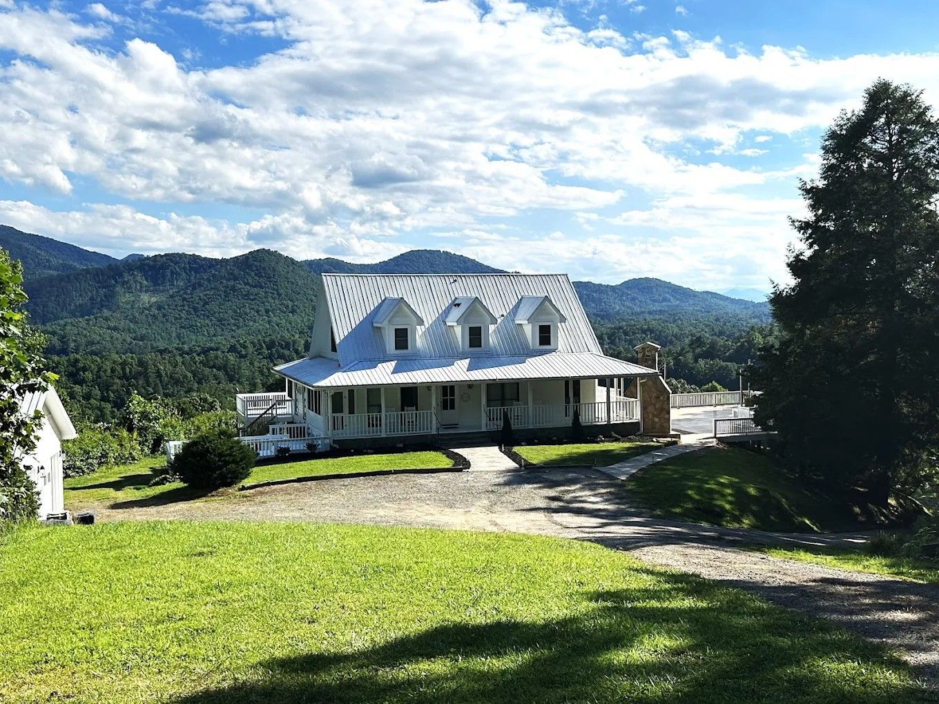 Scenic panoramic collage of a mountain property with green pastures and multiple buildings under blue skies with white clouds.
