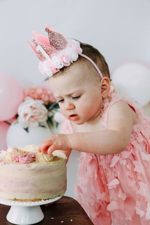 Three sequential images show a cake smash photoshoot featuring a pink tulle dress and white frosted cake.