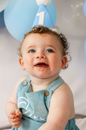 A collection of candid baby photos showing happy expressions and messy chocolate around smiling face in light blue clothing.