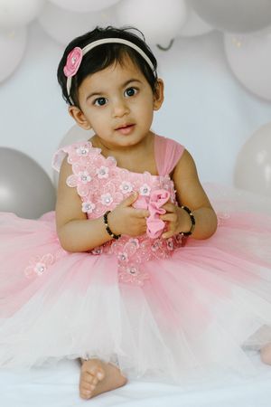 Baby wearing a pink and white tutu dress poses in four different positions on a white background.