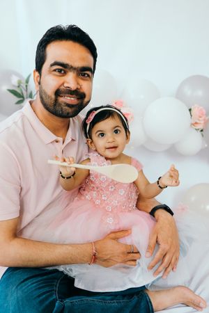 A family photoshoot with pink decor and white balloons featuring warm tender moments between parent and child.