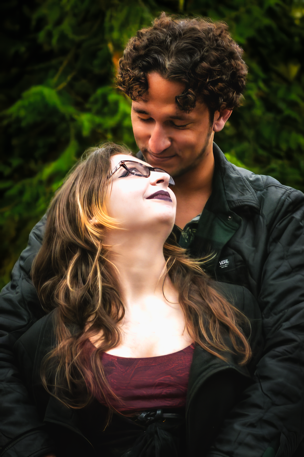 A romantic couple sharing an intimate moment outdoors with natural greenery in the background.