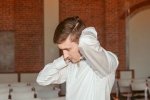 Figure in white dress shirt moves through sunlit brick-walled interior space.