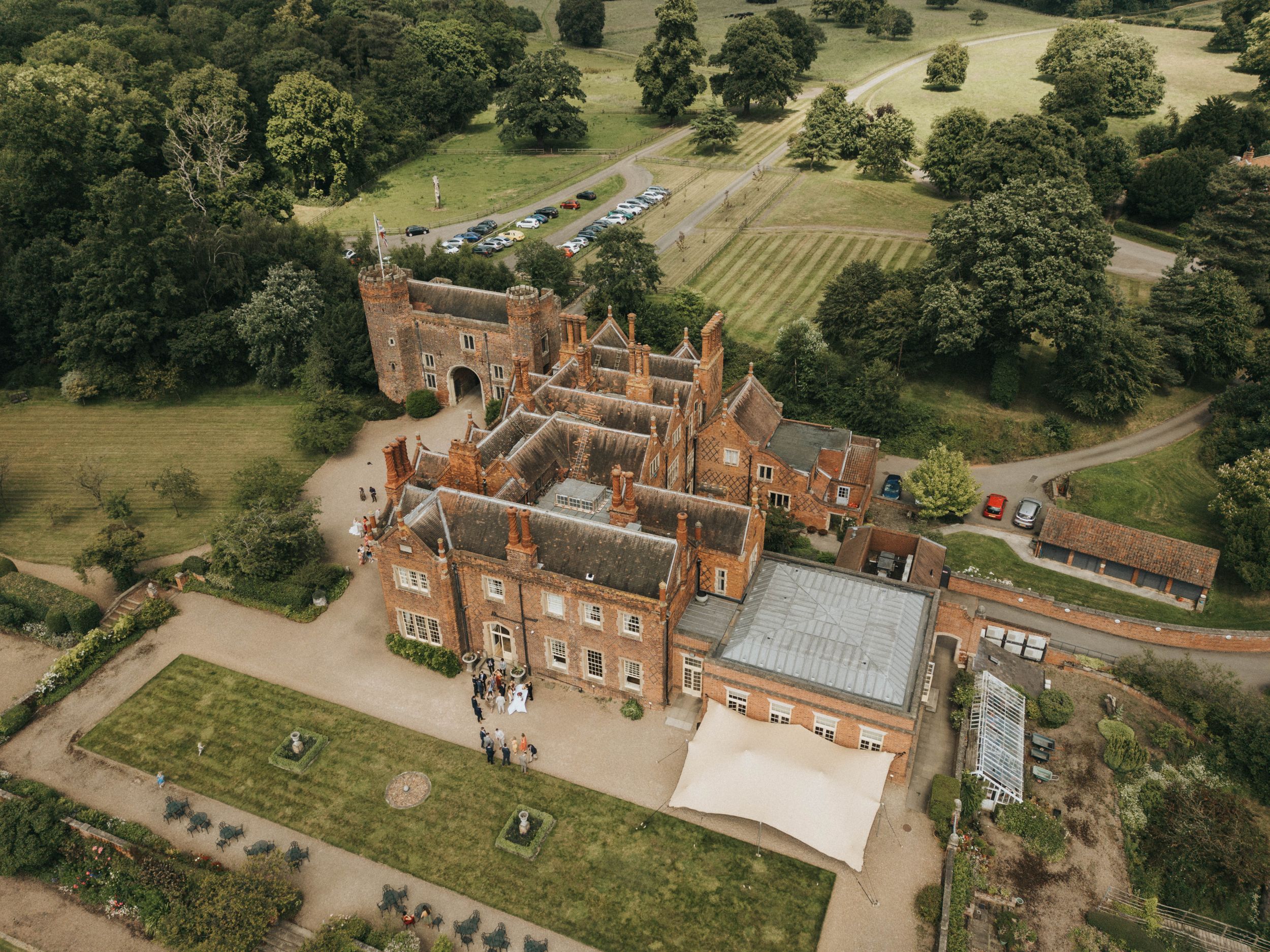 Aerial view of Ingatestone Hall, a grand Tudor brick mansion with extensive gardens and grounds in Essex, England.