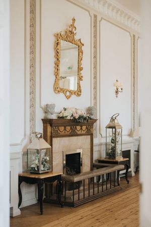 Elegant Victorian fireplace with ornate gold mirror, display cases and decorative molding in a classic interior setting.