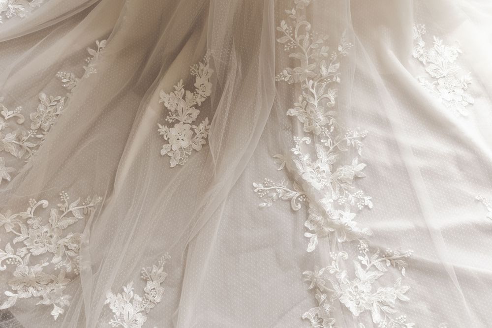 Delicate white lace floral appliques on sheer tulle fabric create an elegant wedding dress detail.