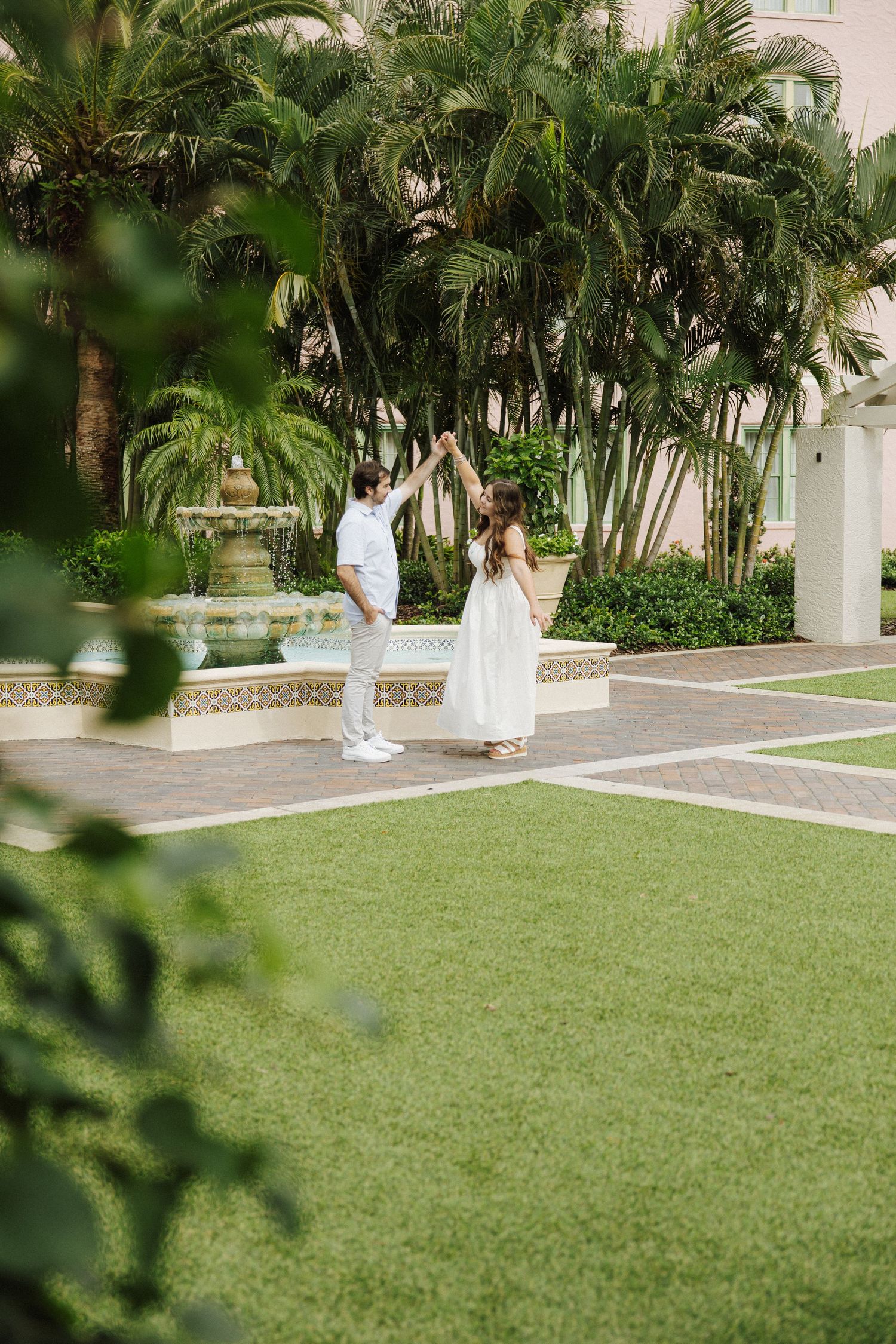 Three serene wedding photos with white dresses on a manicured lawn bordered by tropical palm trees and architecture.
