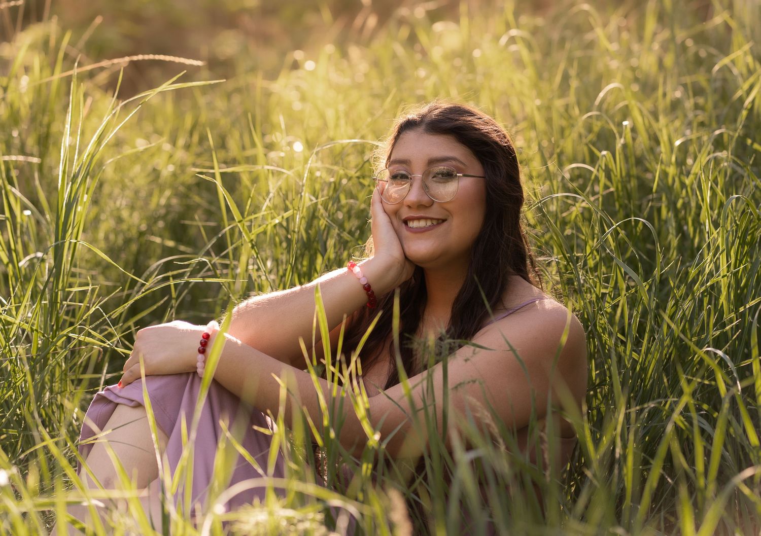 Young girl smiling for her senior portraits in grass in Cache Valley northern UT location.