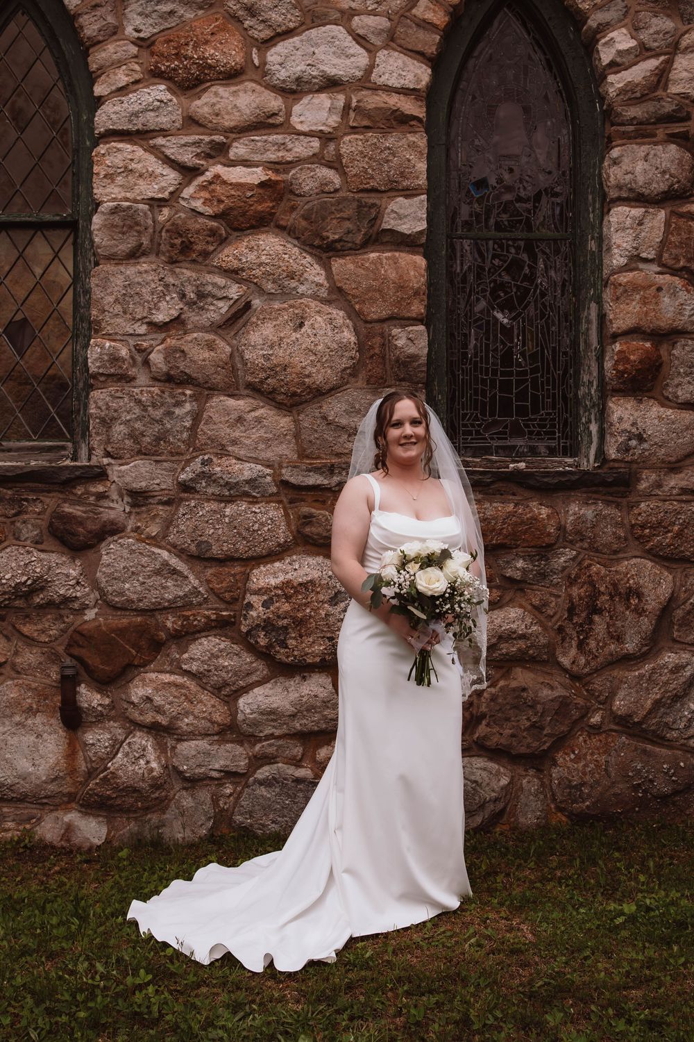 Bride holding bouquet outside of cragsmoor stone church in hudson valley NY
