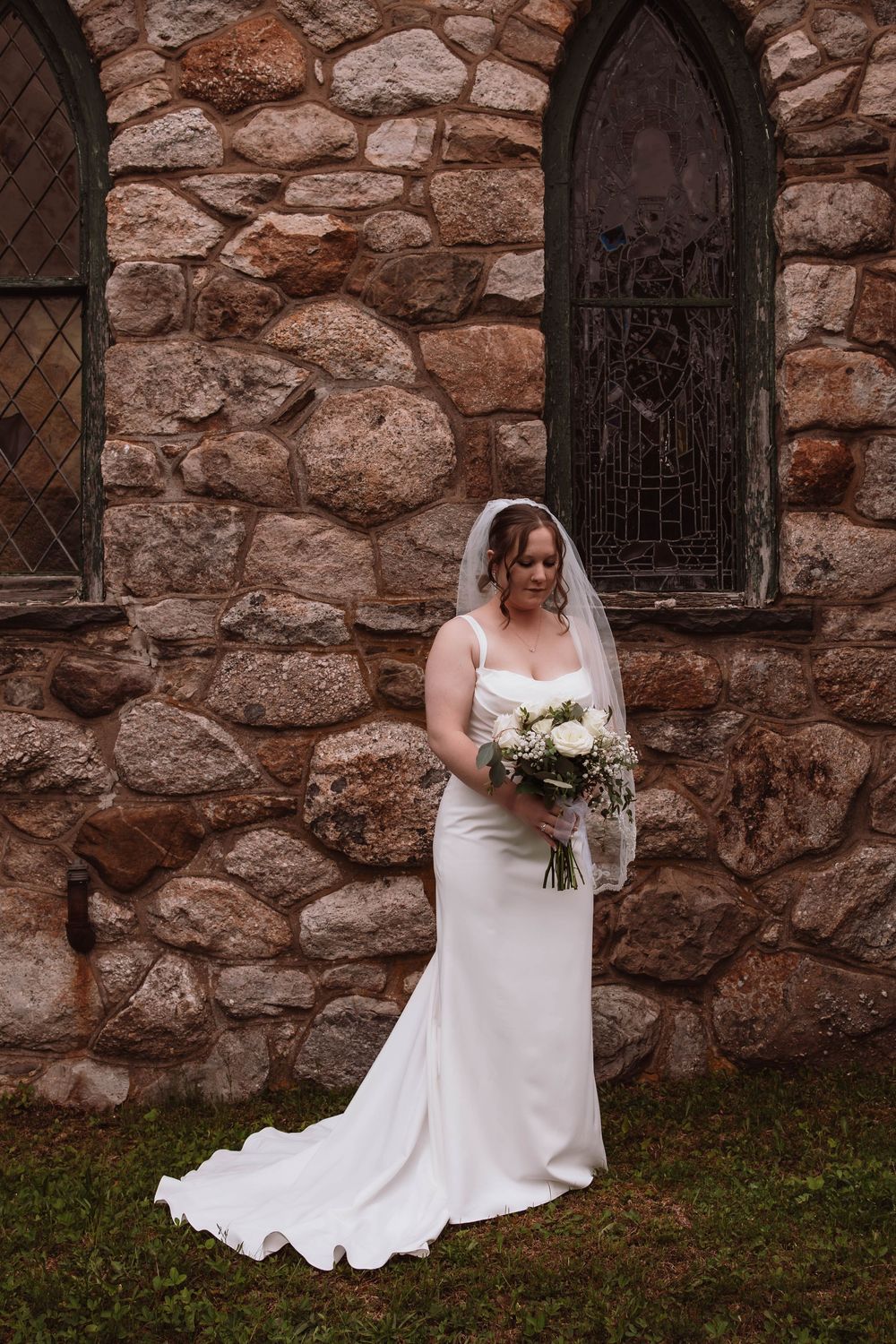Bride holding bouquet outside of cragsmoor stone church in hudson valley NY