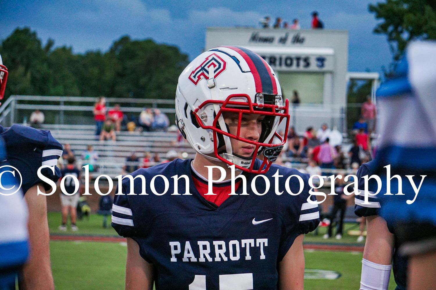 Parrott Academy football player number 15 in navy uniform and red helmet stands on the field during a game.