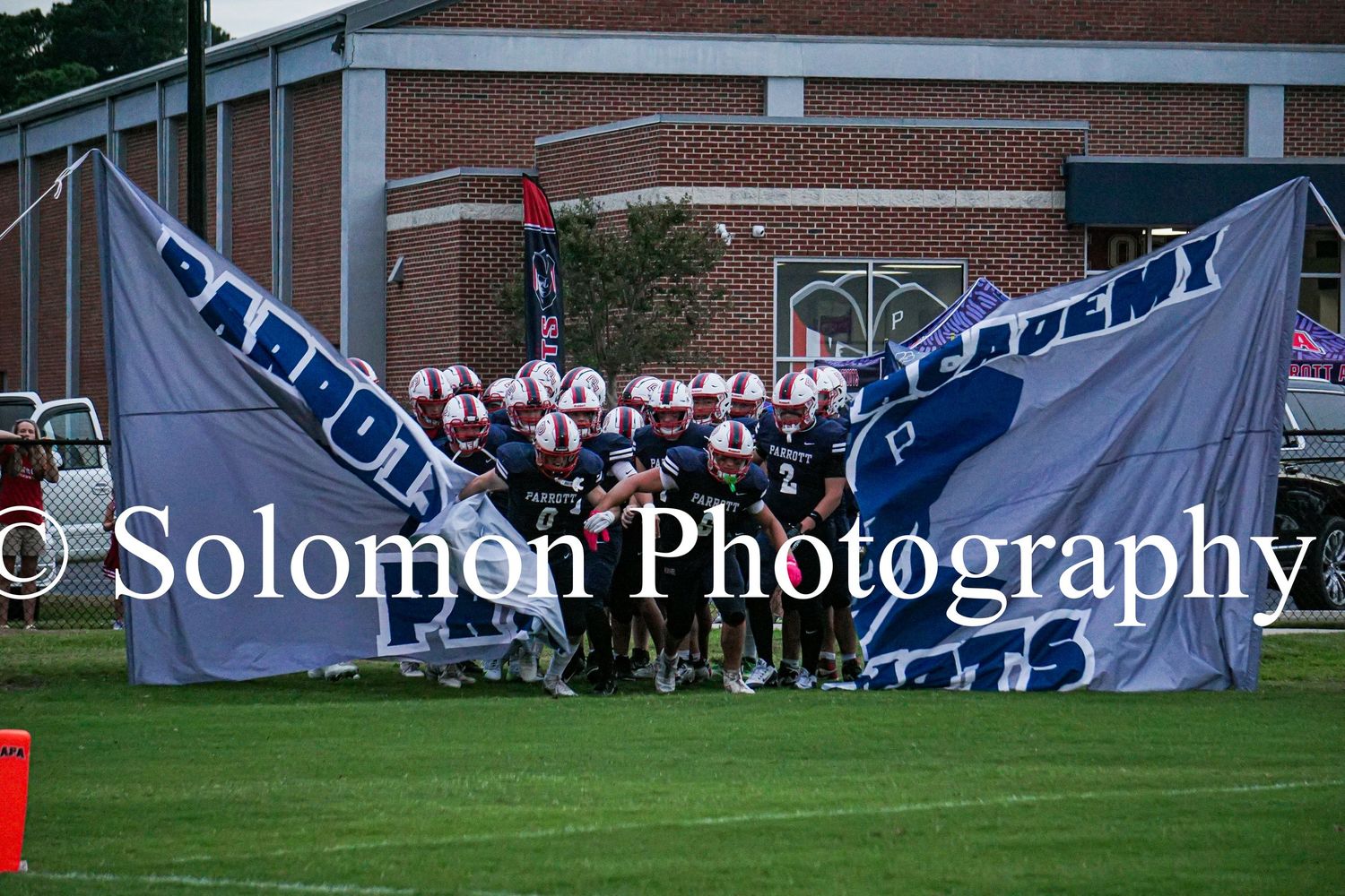 Parrott Academy football team bursts through a large banner onto the field before a home game.
