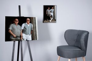 Two framed photographs displayed on a white wall next to a modern grey accent chair.