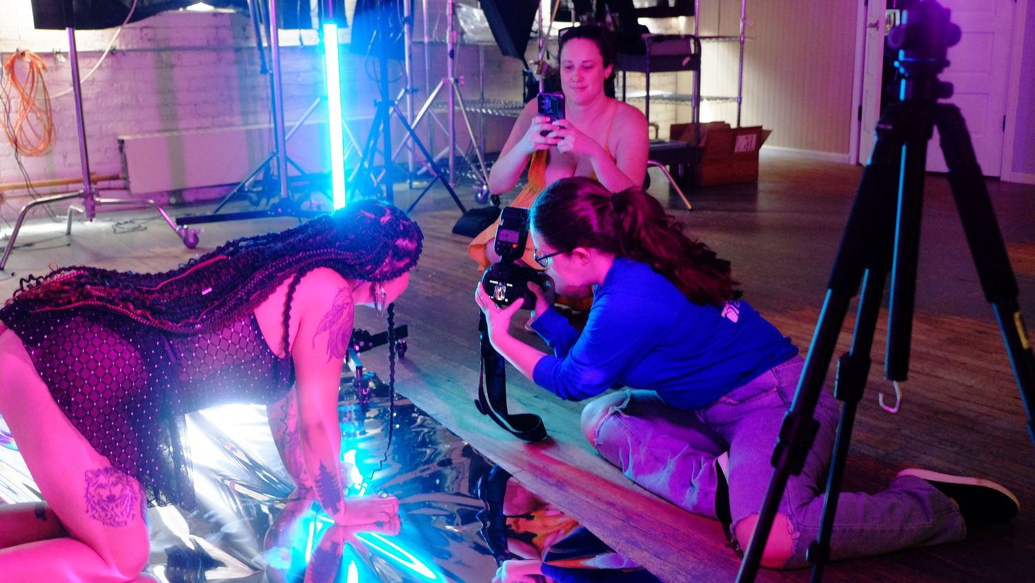 A modern gym space features blue and pink LED lighting illuminating several workout machines in a dark atmosphere.