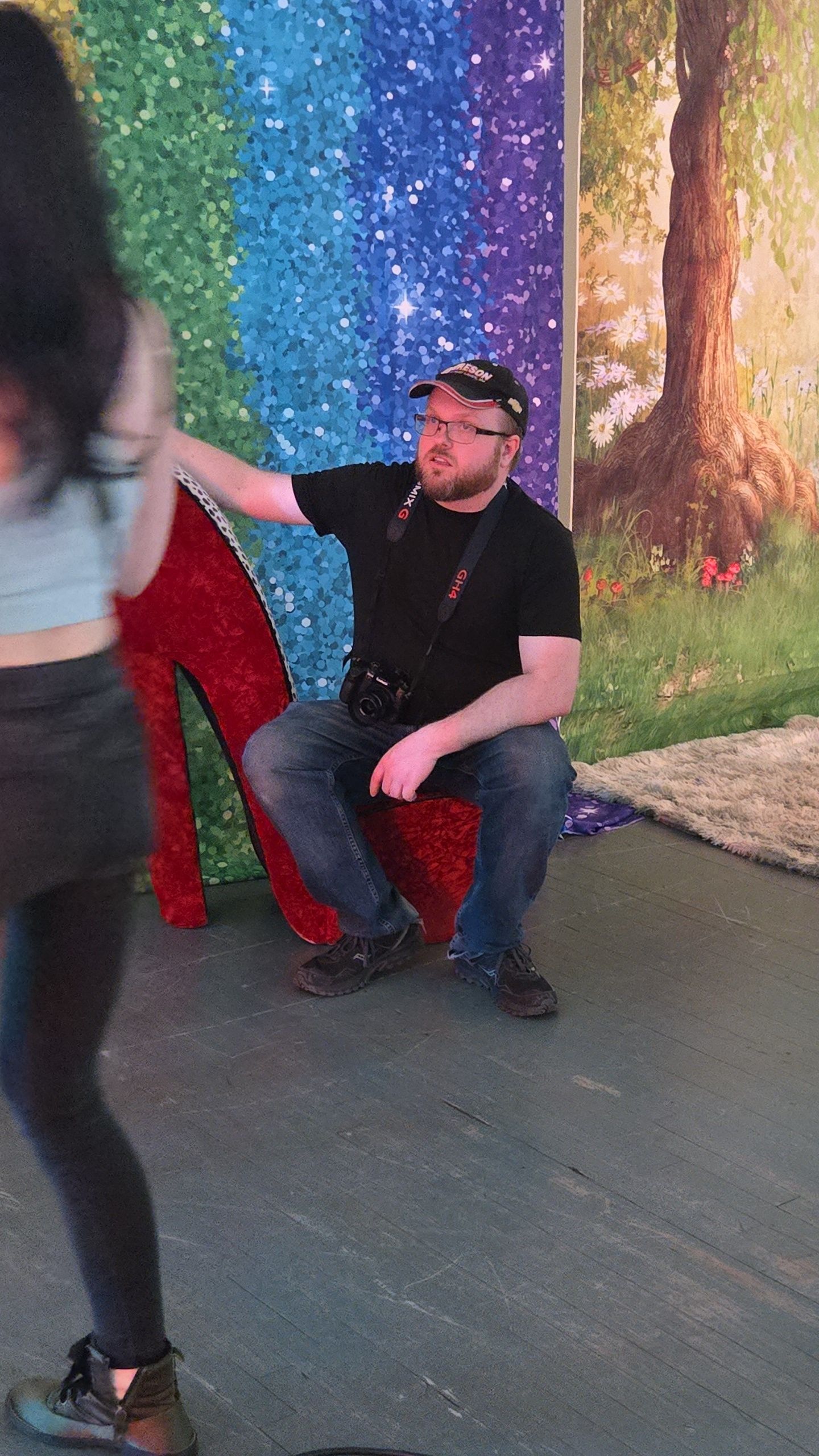 Photography session in front of a sparkly rainbow backdrop with red chair prop.