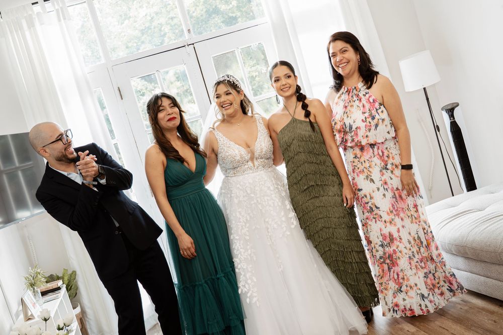 Group poses together in formalwear at an elegant indoor event, with bright natural light from windows.