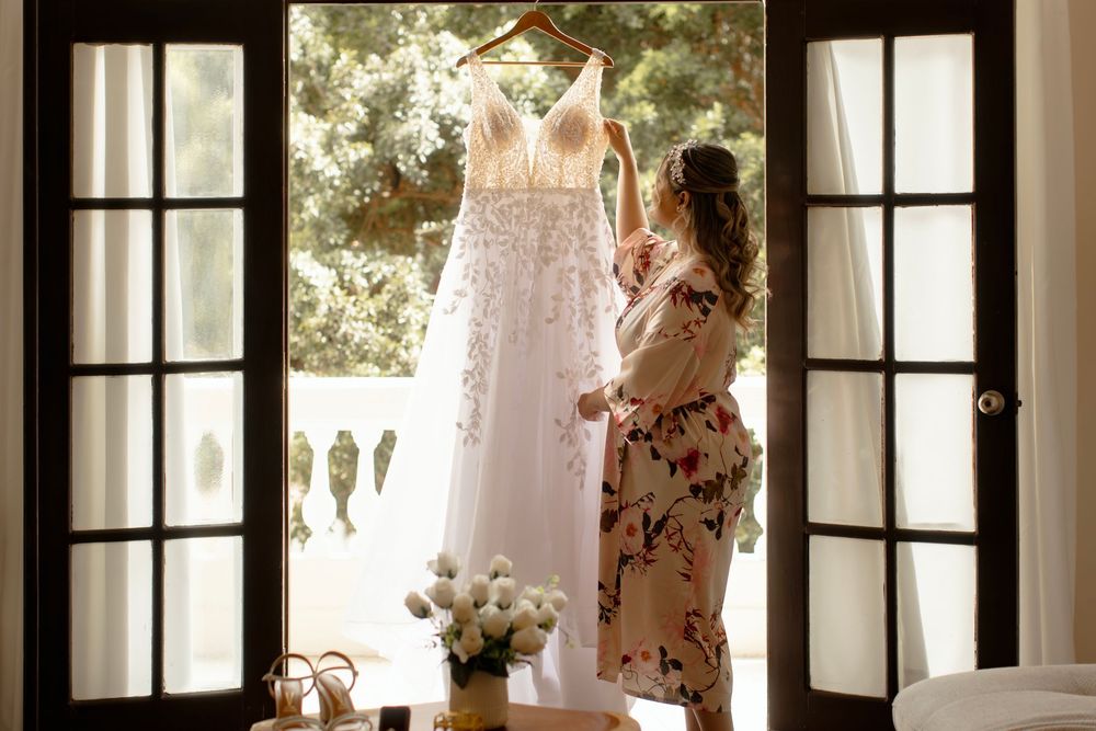 Elegant white wedding dresses hang in sunlit windows of a bridal boutique, creating a dreamy atmosphere.