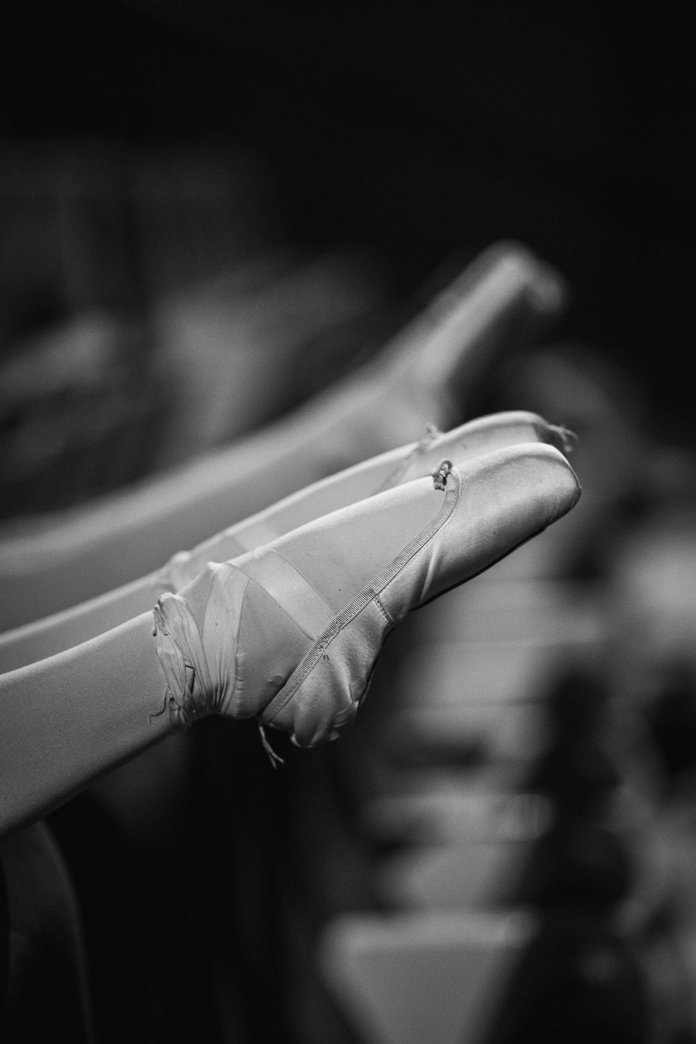 Black and white close-up images of a ballet dancer's pointe shoes showing graceful foot positions in sequence.