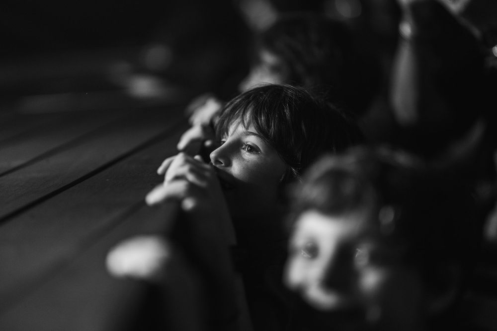 A black and white image of two children looking up in wonder, captured in a soft moody lighting.