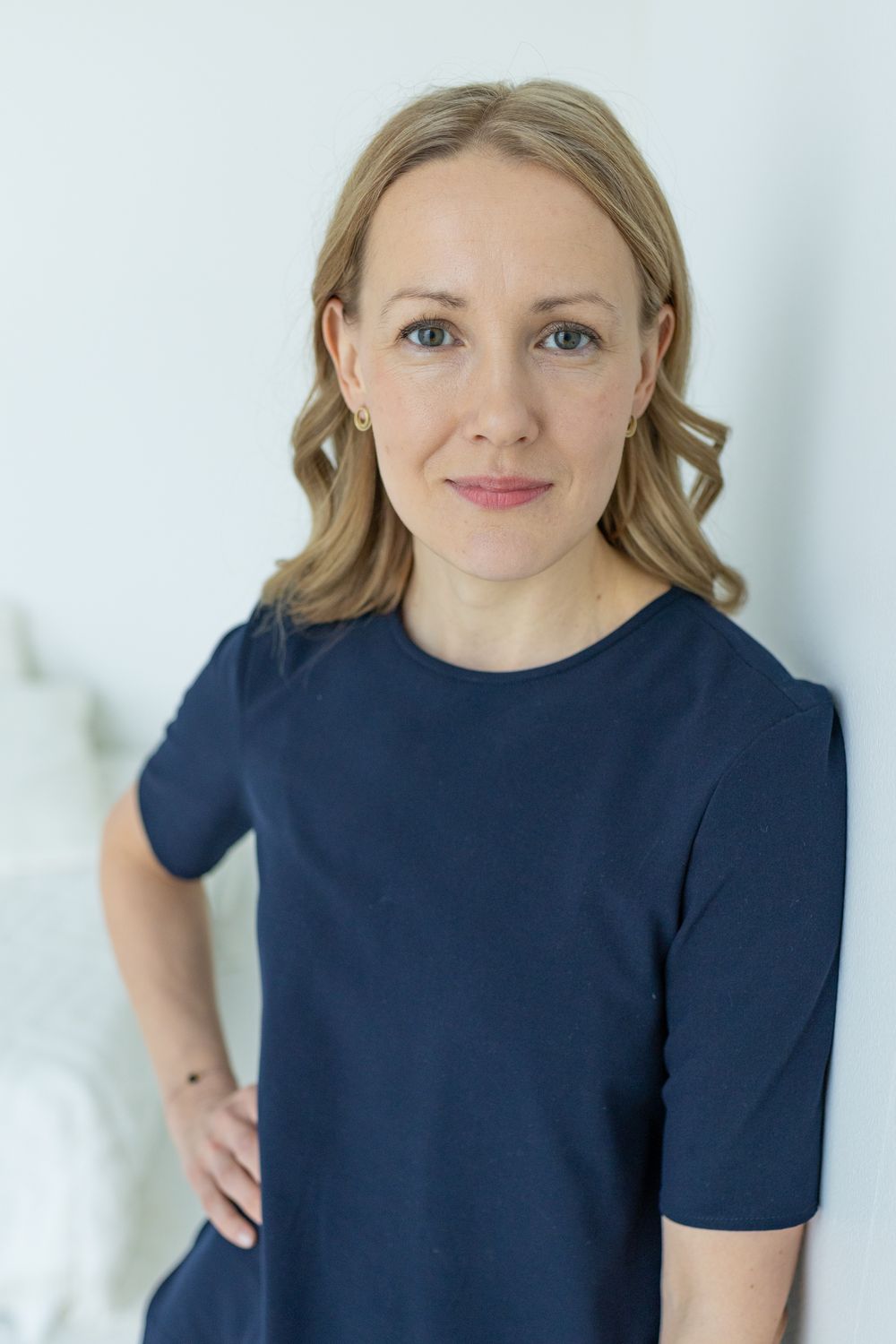 Henkilökuvaus studiolla. Nainen tummissa vaatteissa nojaa sivuttain seinään, käsi lantiolla. Valokuvaaja Annina Nygård.