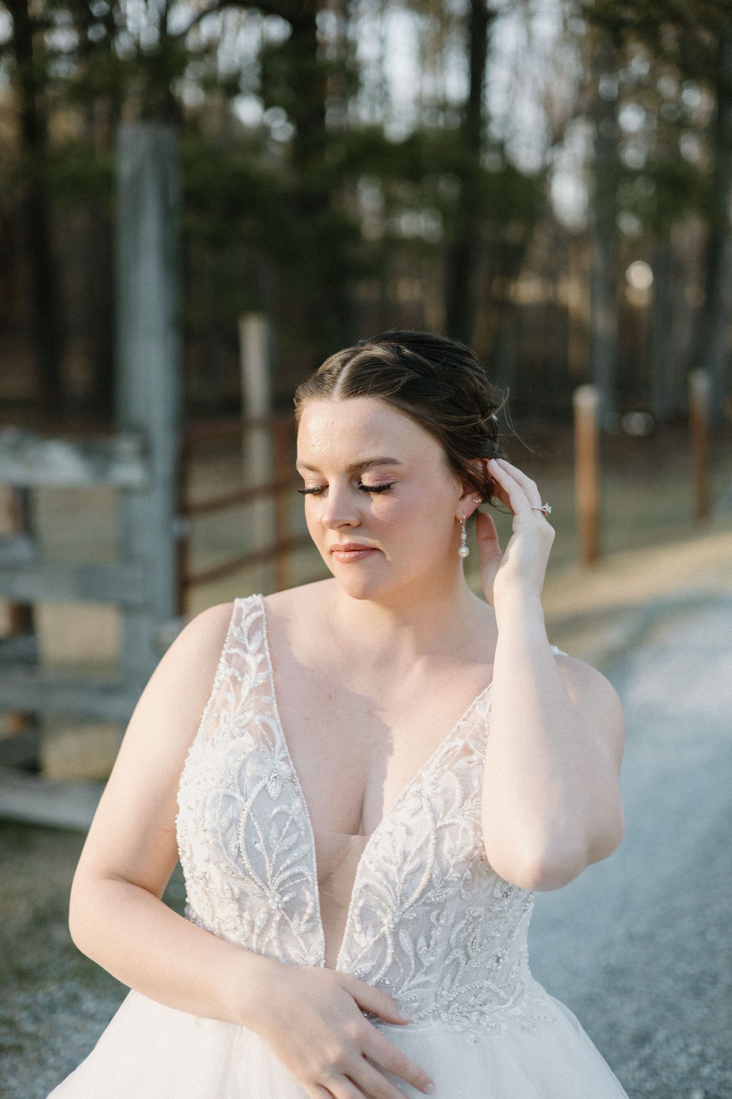 Bride in a plunging V-neck lace wedding dress poses against snowy winter landscape outdoors.