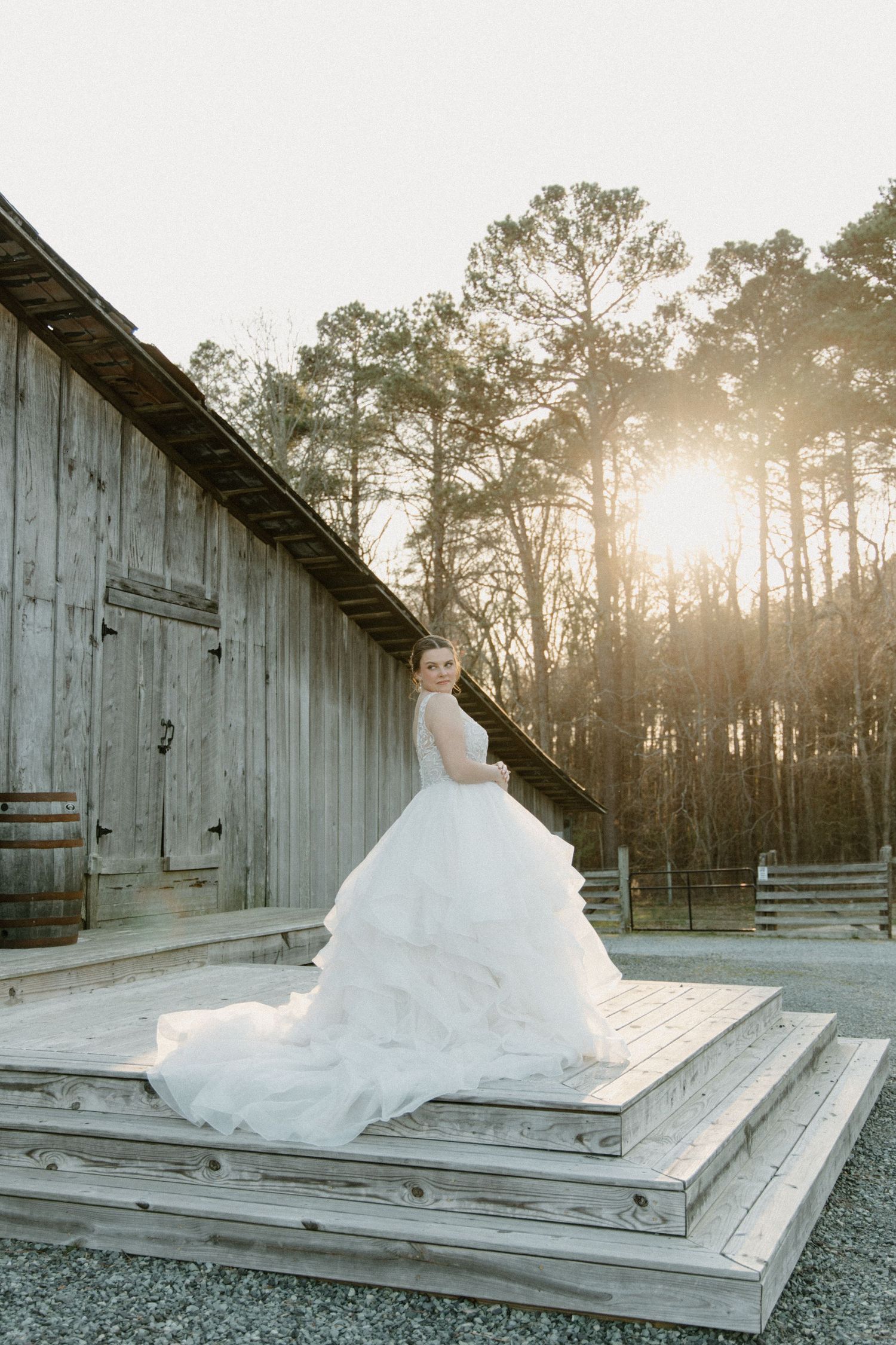 A snow sculpture takes shape on wooden steps against a rustic barn backdrop in golden winter sunlight.