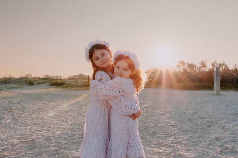 Golden sunset light illuminates a couple wearing white as they embrace on a sandy beach during a photo session.
Altona Family Photographer