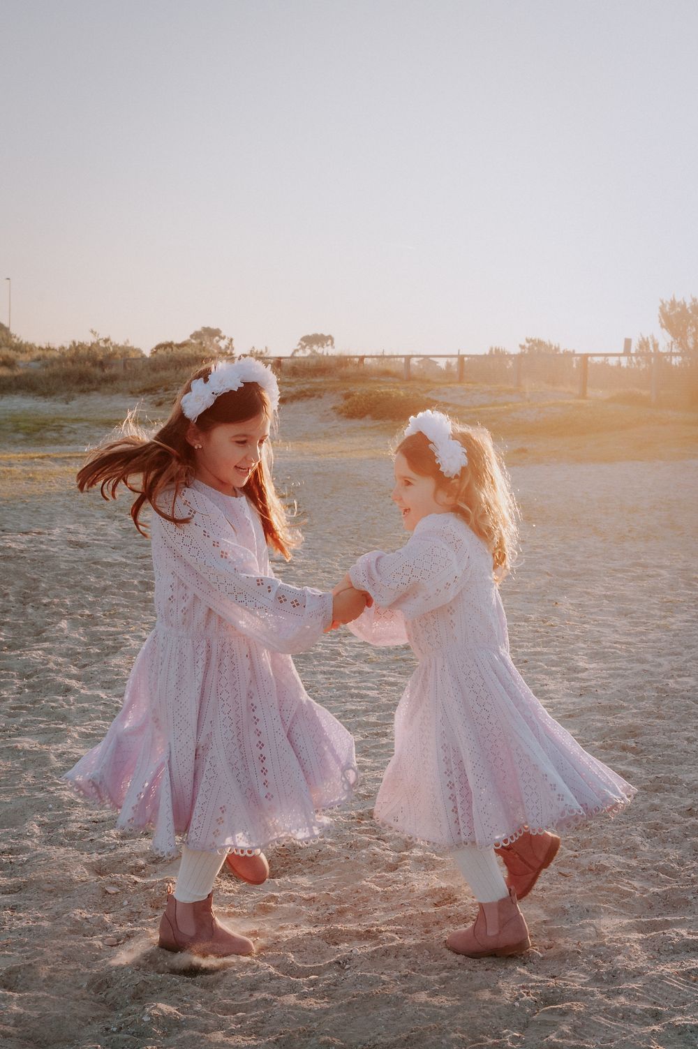 Two children in matching white dresses dance playfully together on a sandy beach at sunset.
Altona Family Photographer Melbourne