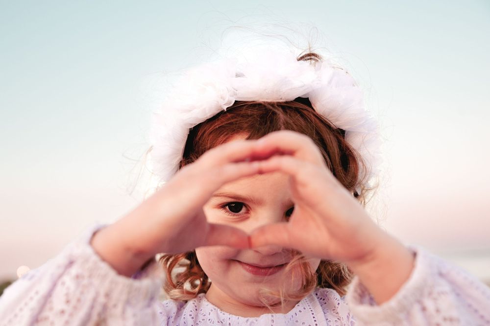 A child peeks through their heart hands in a playful peek-a-boo gesture against a white background.
Altona Family Photographer Melbourne