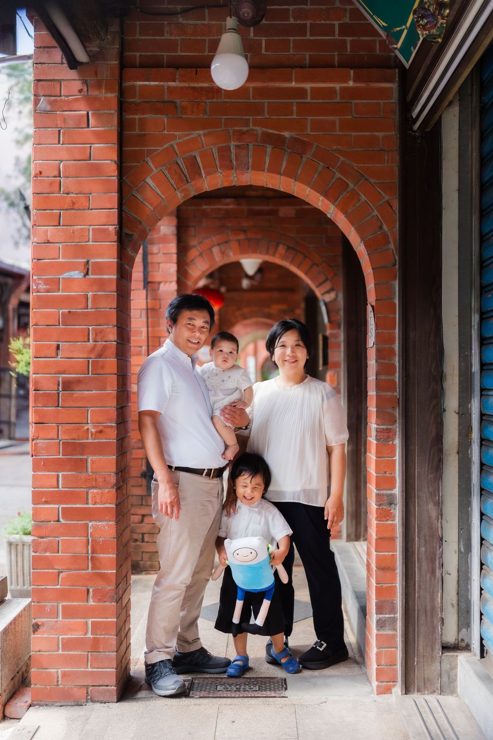 Family members pose together under brick archways of a traditional building.