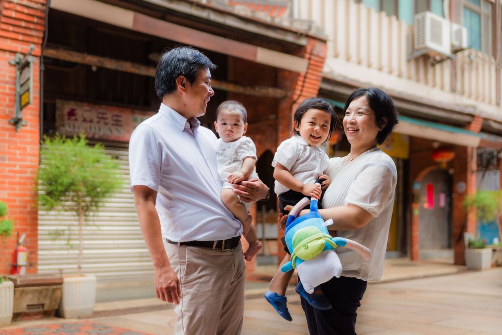 A family shares tender moments together along a brick-lined walkway on a sunny day.
