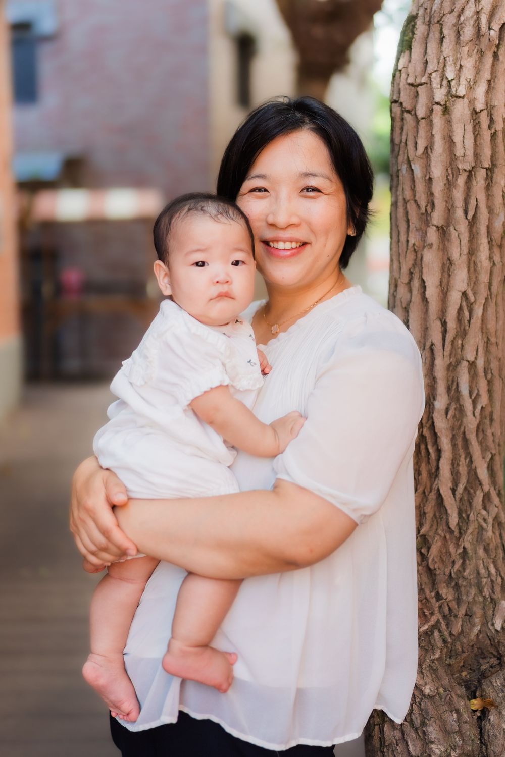 A tender moment captured between parent and baby against a tree backdrop.