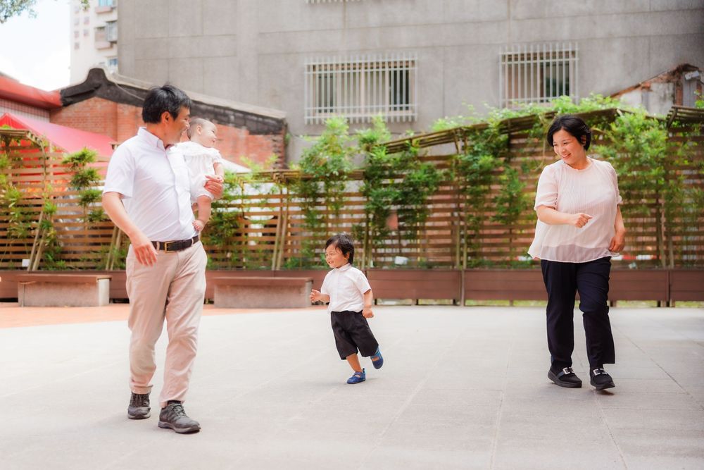 Students in white uniforms practice martial arts moves in an outdoor courtyard.