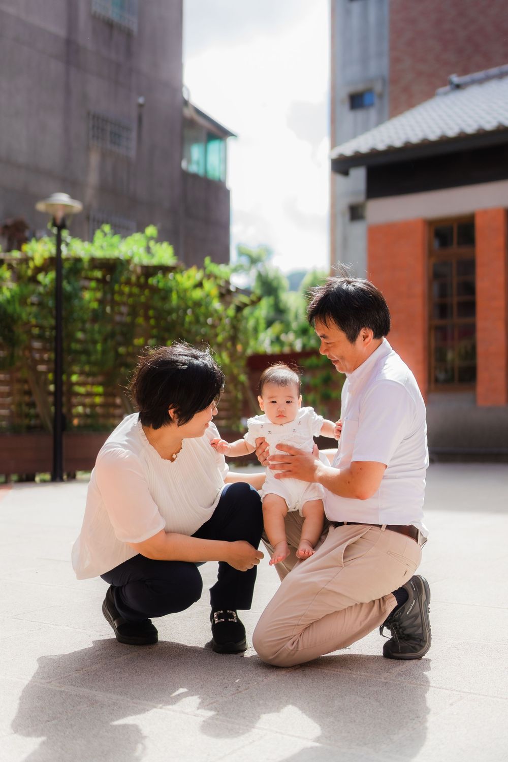 A family sits together on a concrete floor in a series of playful poses captured across multiple photos.