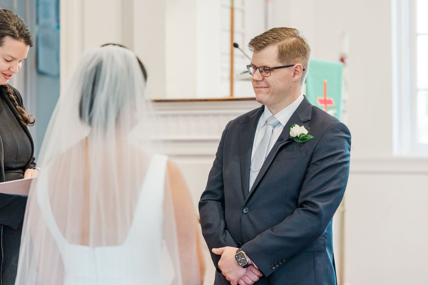 A couple exchanges vows during an intimate church wedding ceremony with soft natural lighting.