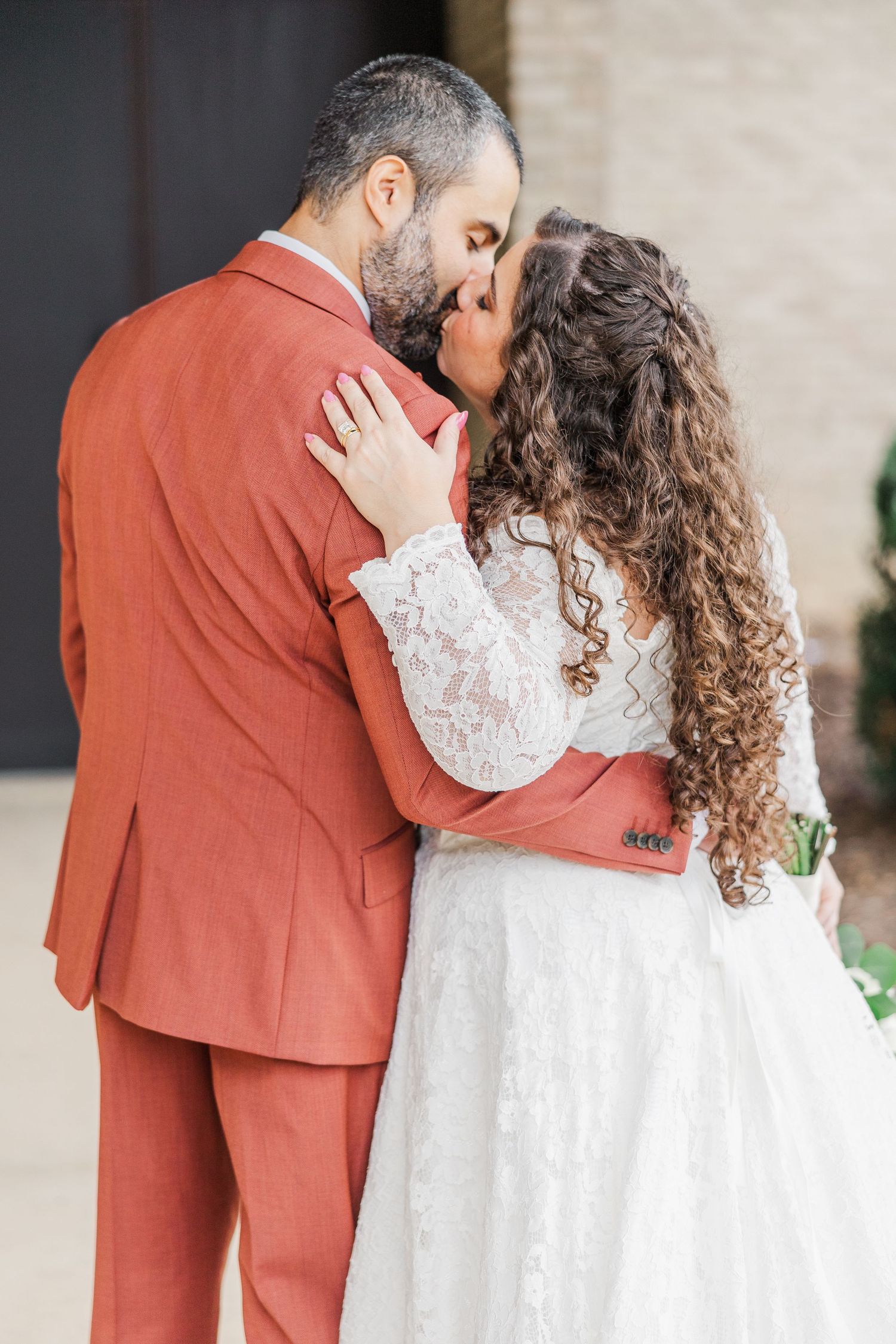Romantic couple in rust suit and white lace dress embrace in intimate wedding photo sequence.