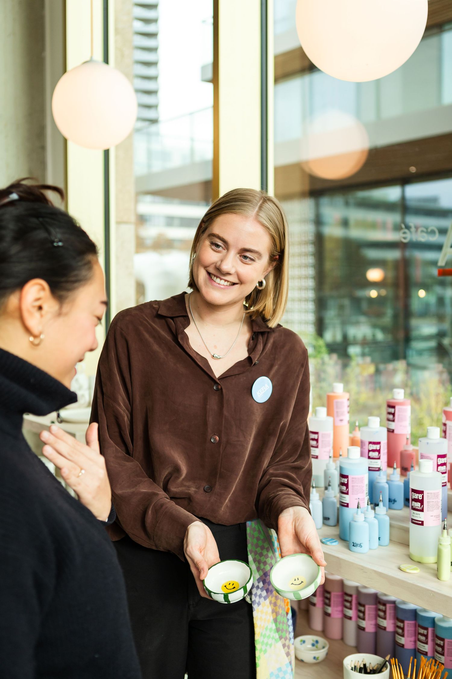 Two people in a retail store examining colorful product bottles on shelves while having a friendly conversation.