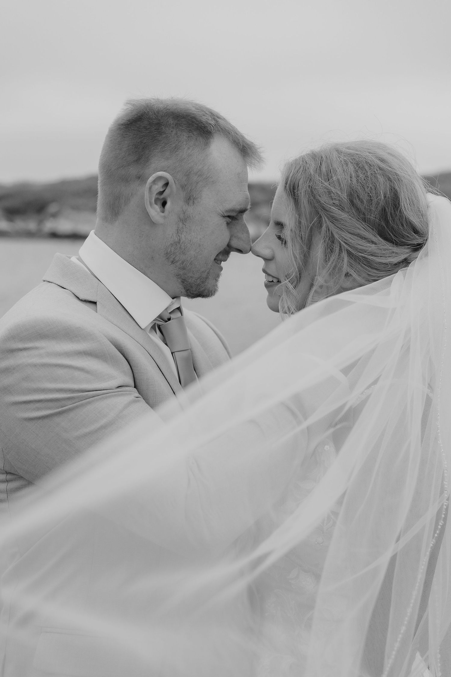 Black and white wedding portrait series showing romantic close-up moments between newlyweds with flowing bridal veil.
